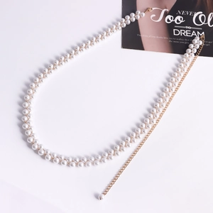 Dettaglio di elegante catena per il corpo in perle a doppio filo con chiusura dorata