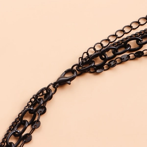 Macro detail of multi-layered black chain necklace featuring a lobster clasp and industrial links