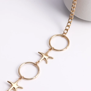 Macro detail of gold starfish and circular ring links on a stylish metal body chain