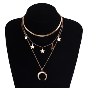 Dettaglio collana punk dorata a strati con ciondoli a stella e luna su modello nero