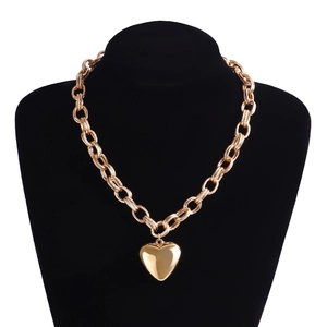 Detail of chunky golden chain necklace featuring a large polished heart pendant on display