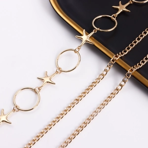 Detailed close-up of golden metal starfish and ring body chain on a luxury tray