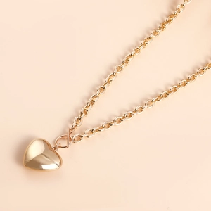 Macro view of gold chunky chain with OT buckle and polished heart-shaped pendant