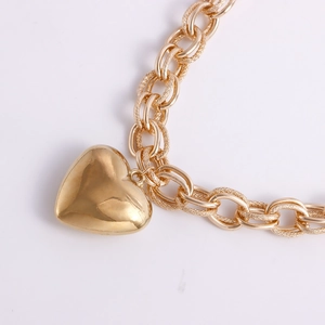 Close-up of golden textured chain links and polished heart pendant on white background