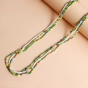 Detail of bohemian layered colorful seed bead necklace featuring golden butterfly pendants
