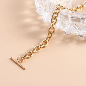 Macro detail of gold chunky chain with classic OT toggle clasp on a crystal glass edge