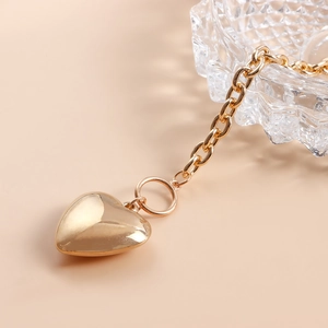 Golden OT buckle chain with a large heart pendant on a warm beige background