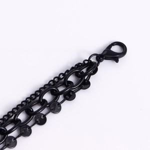 Detail view of multi-layered matte black chains with secure lobster clasp and ring charms