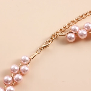 Dettaglio di perle rosa con chiusura a moschettone dorata e catena in metallo regolabile