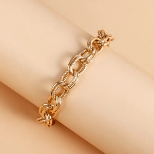 Detail of gold metal chunky chain bracelet featuring smooth and textured oval link rings