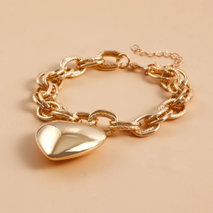 Detail of chunky gold heart pendant with thick textured metal chain and lobster clasp