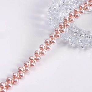 Dettaglio macro di perle rosa in filo dorato intrecciato a doppia fila per catena corpo