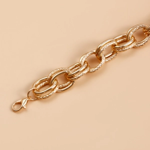 Detail of chunky gold chain showing smooth and textured links with a lobster clasp closure