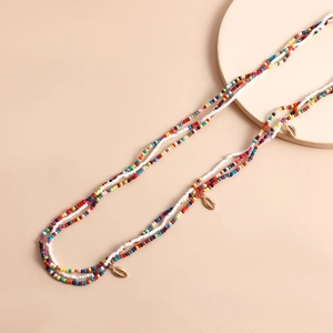 Close-up of bohemian colorful seed bead body chains with gold seashell pendants
