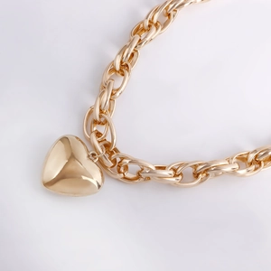 Detail of chunky gold chain link necklace with a polished 3D heart pendant charm