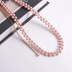 Dettaglio della catena in perle rosa con maglie dorate e pendente a forma di perla