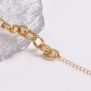 Close-up of gold chunky chain bracelet with polished rings and textured finish