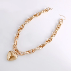 Close-up of golden chunky chain necklace with a polished large heart pendant and lobster clasp