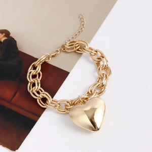 Macro detail of bold golden heart pendant necklace with thick hip-hop link chain