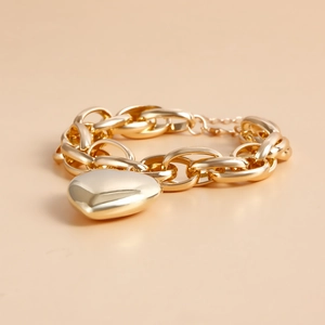Detail of chunky gold cable chain bracelet with heart charm and lobster clasp