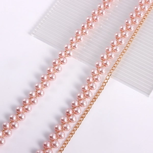 Dettaglio della catena in vita con perle rosa e maglie dorate e trama intrecciata