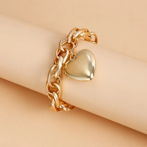 Detail of chunky gold chain necklace with large heart pendant on a display stand