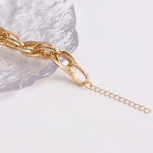 Detail of chunky gold chain bracelet with toggle clasp and large heart pendant on glass tray