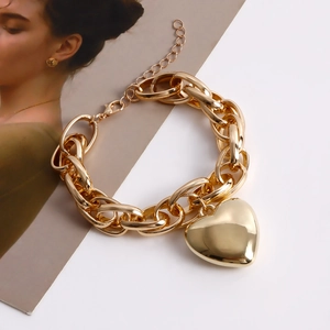 Close-up of golden chunky chain necklace with a large heart pendant on a white background