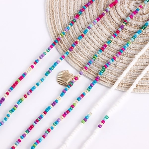 Close-up of bohemian beaded body chain with gold shell pendant on a woven mat