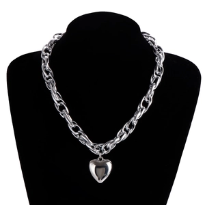 Close-up of polished silver heart pendant on chunky metal chain necklace on neck model