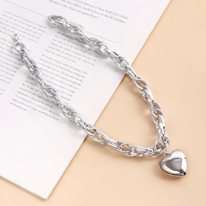 Close-up of chunky silver O-chain necklace with a bold heart pendant and lobster clasp
