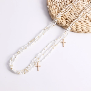 Detail of bohemian layered waist chain with white beads and golden cross pendants