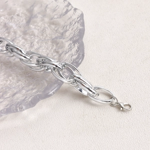 Detail of silver chunky oval link chain bracelet with metal lobster clasp on textured surface
