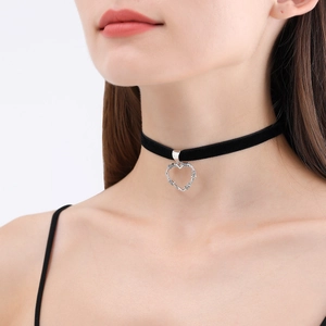 Dettaglio di un choker in velluto nero con ciondolo a cuore argentato testurizzato sul collo