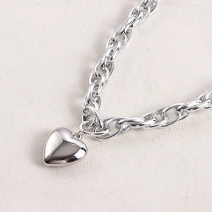 Close-up of a chunky silver chain necklace featuring a polished 3D heart-shaped pendant
