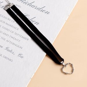 Dettaglio di girocollo in velluto nero con ciondolo a cuore in argento dal design gotico