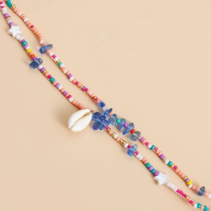 Detail of beaded waist chain with colorful beads, blue stones and a white seashell charm