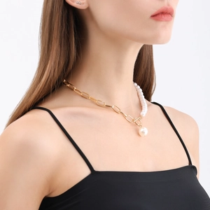 Detailed close-up of a gold link chain and pearl necklace with a vintage toggle clasp design