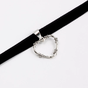 Dettaglio choker di velluto nero con ciondolo a cuore in stile filo spinato metallico