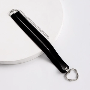 Dettaglio di choker in nastro nero con ciondolo a cuore in argento e trama a spine