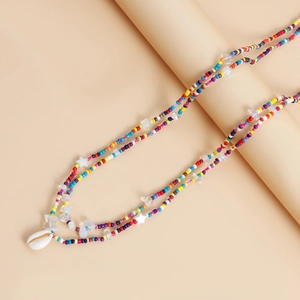 Detail of colorful beaded body chain featuring a white seashell pendant and starfish beads