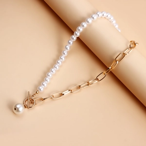 Detailed view of two-tone pearl necklace with gold OT buckle and pendant on beige base
