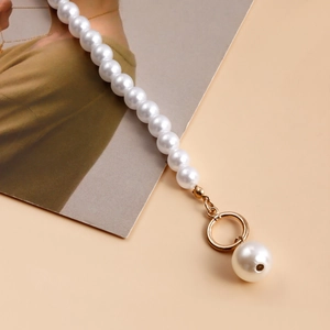 Macro shot of faux pearl necklace with golden OT buckle and baroque pearl pendant