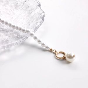 Close-up of white pearls necklace with golden OT clasp and a large pearl pendant