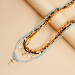 Detail of bohemian four-layer beaded necklace featuring EMPRESS gold letter charms