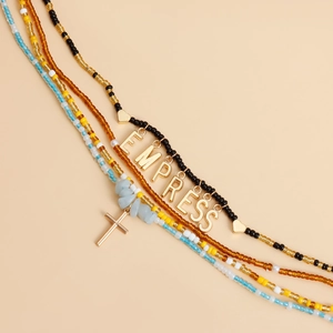 Detail of bohemian layered beaded waist chains with shells and Empress letter pendant