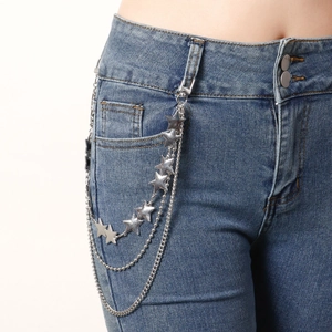Macro shot of silver multi-layered metal waist chain with stars on denim jeans