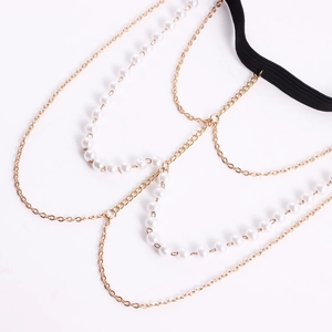 Primer plano de cadenas doradas de varias capas y perlas blancas en banda elástica