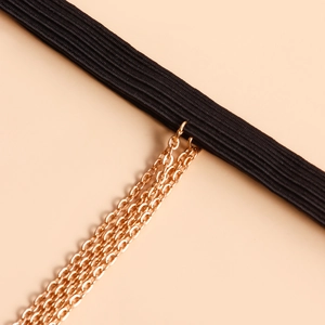 Dettaglio catena da gamba elastica nera con frange dorate e perle di imitazione