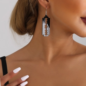 Close-up of stylish black acrylic razor blade earrings on model for a bold punk look